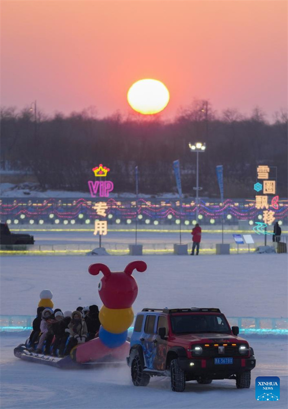 Turistas se divertem ao pôr do sol no Mundo de Gelo e Neve de Harbin, no nordeste da China